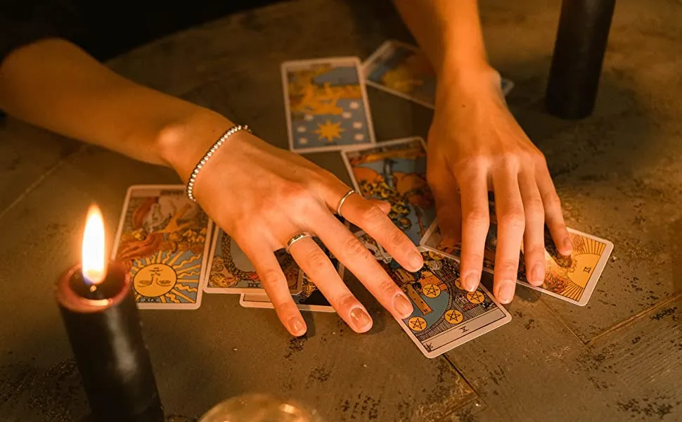 Tarot reading with hands arranging cards and candle