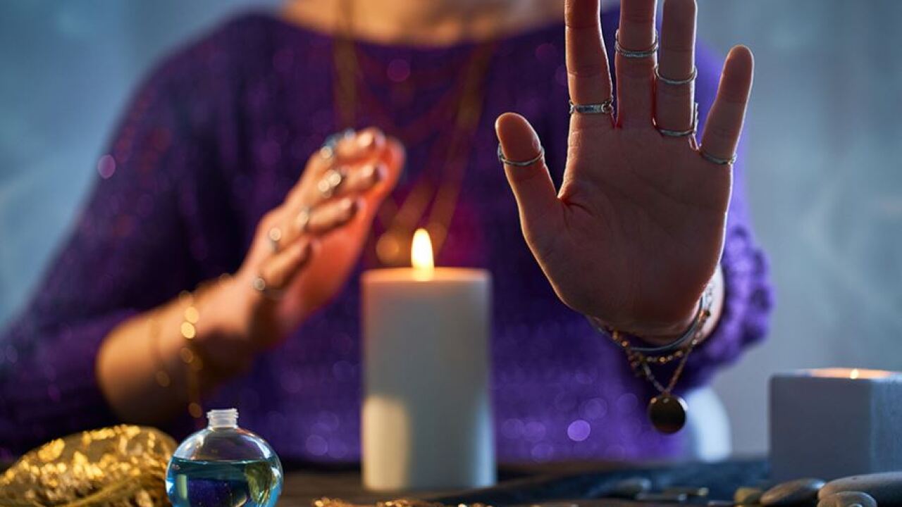 Hands raised near a candle during a tarot reading
